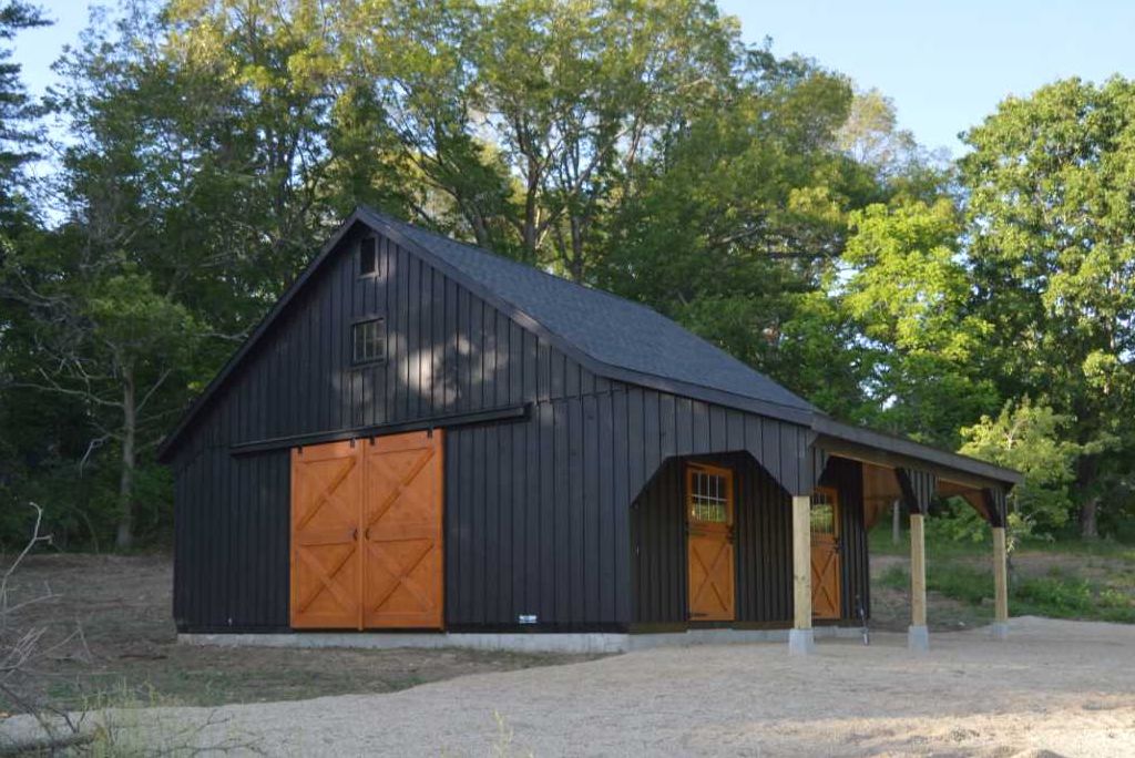 a black shingle type of barn roof on structure in front of trees