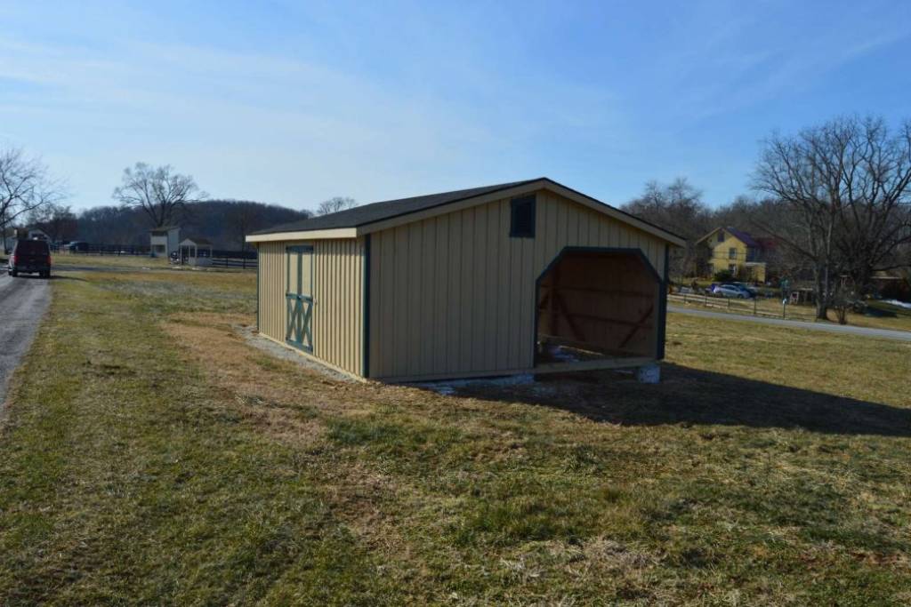 tan mini horse shed with green trim